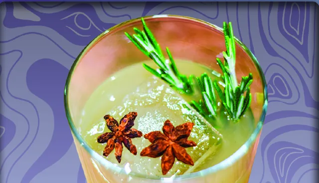 Perspection Punch: a glass of punch over a large ice cube with star anise and rosemary