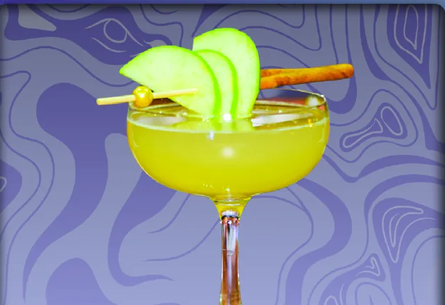 The FoxSwan: a yellow coupe cocktail garnished with apple slices and a cinnamon stick