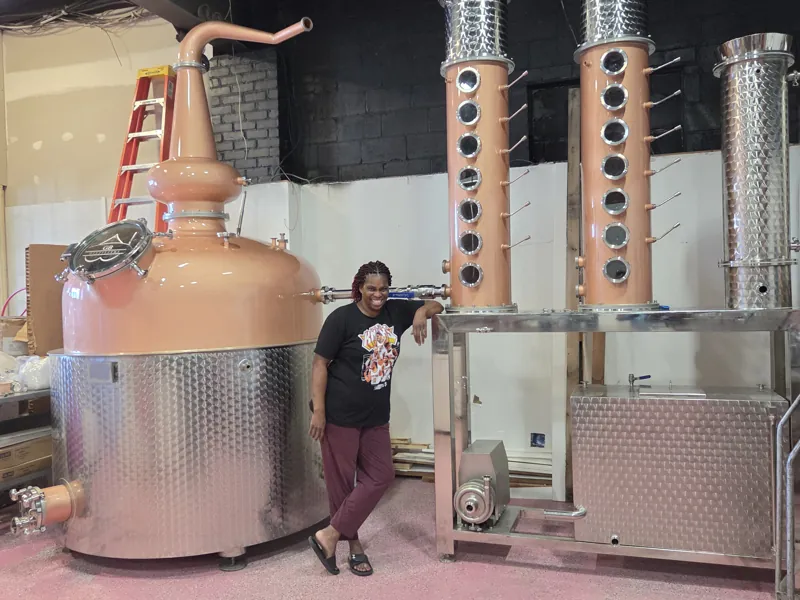 Vanessa Braxton standing beside the copper still at GB Distillers
